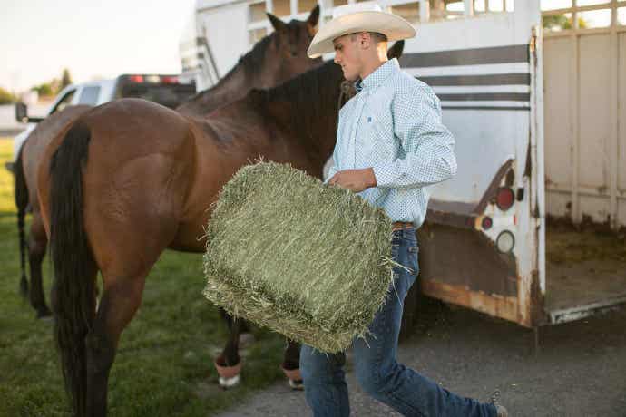 Cowboy holding hay bale