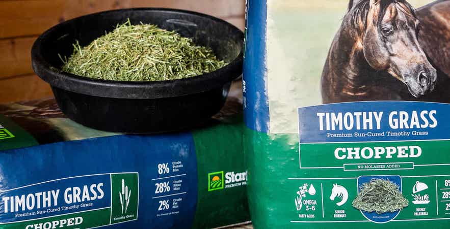 Close-up of feed pan and bags of chopped timothy grass with nutritional information showing.
