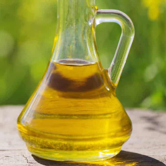 Glass container half-filled with canola oil