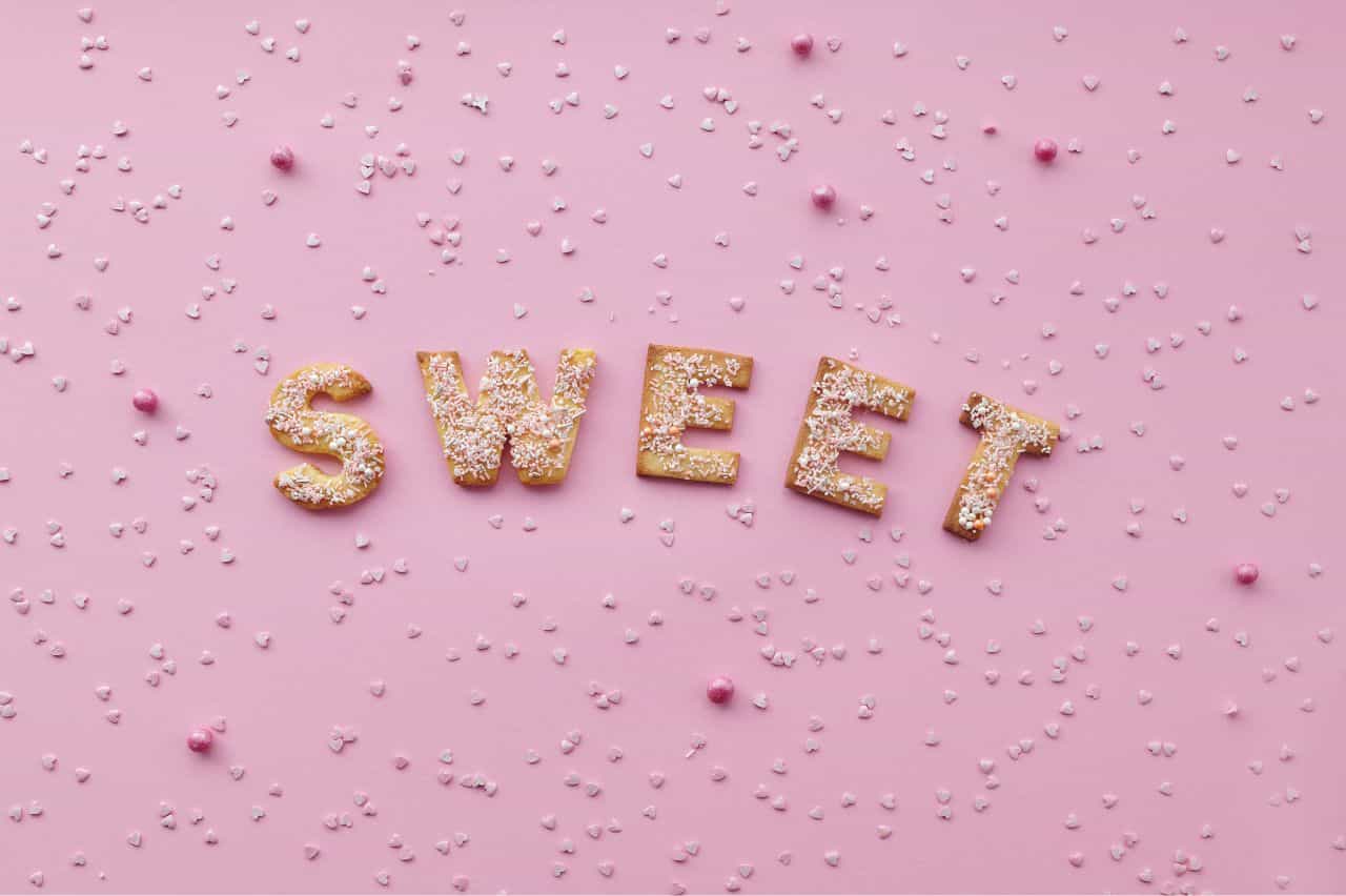 S-W-E-E-T spelled in candy on pink background