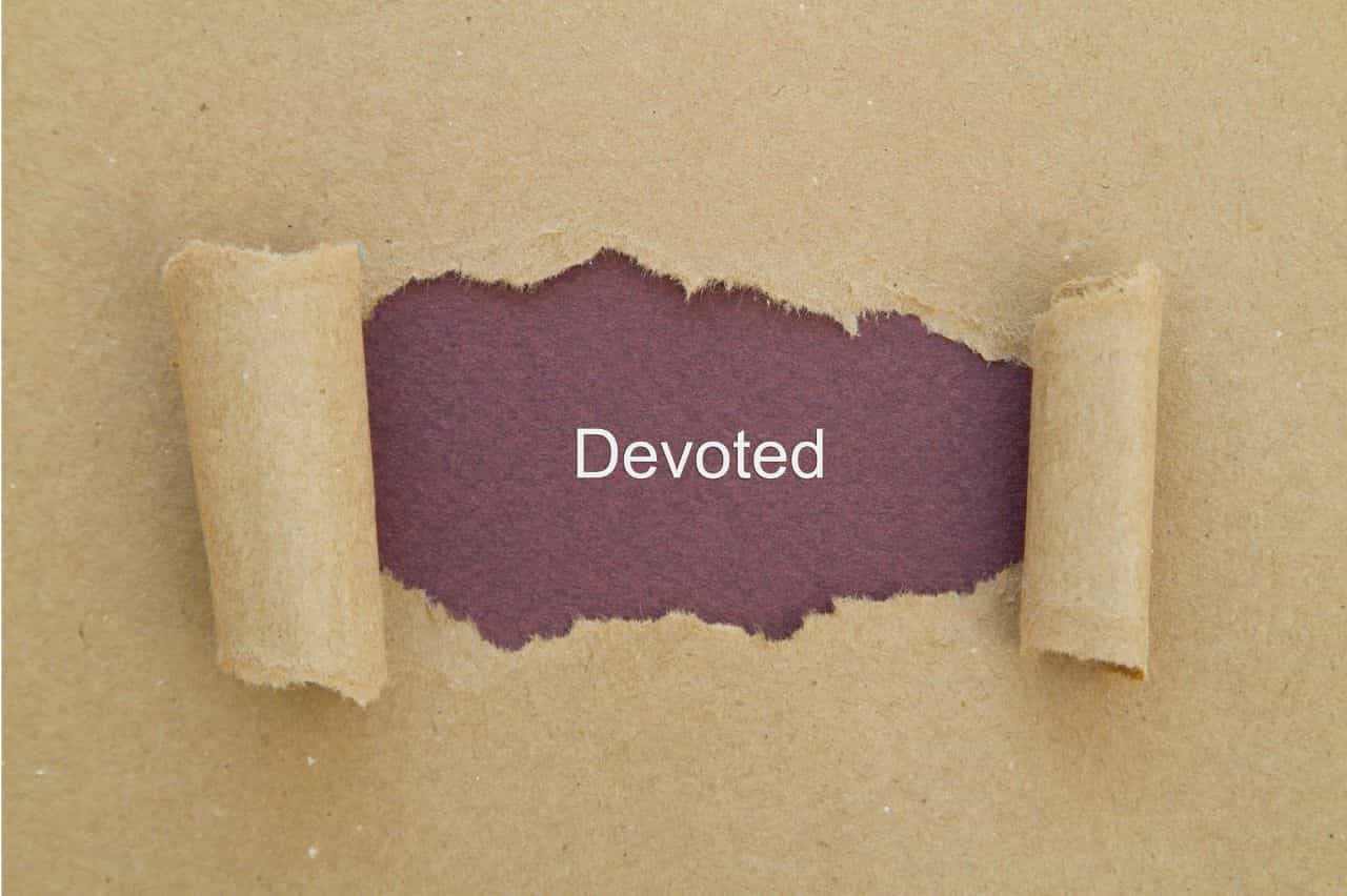 Paper torn away to reveal the word devoted typed underneath
