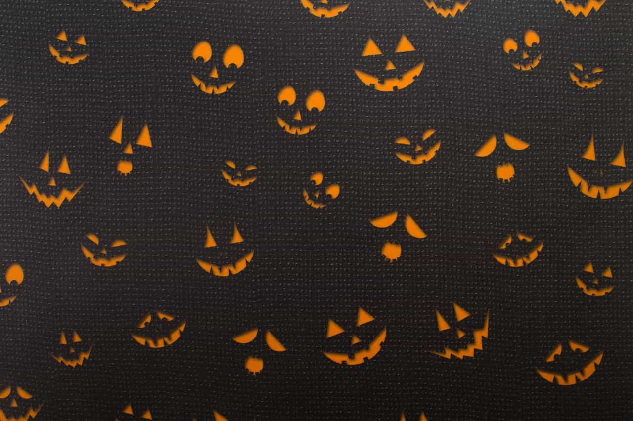 Variety of jack-o-lantern faces glowing orange in the dark