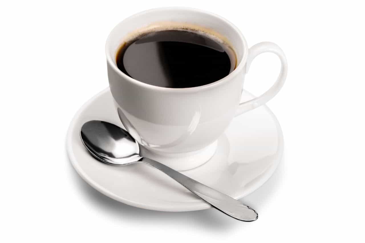 White cup of black coffee with spoon and white dish.