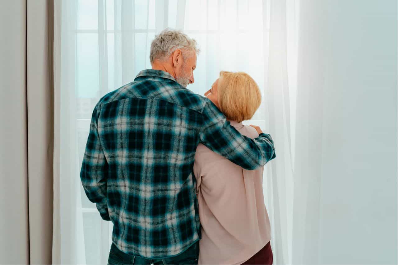 Husband with arm over wife's shoulder seen from behind